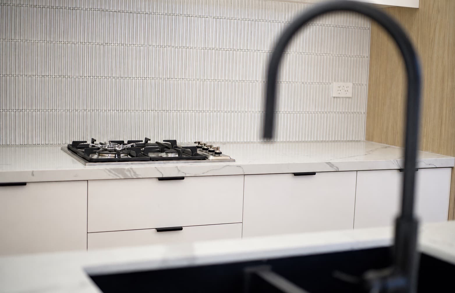 Kitchen with stone benchtop, gas cooktop and black tapware